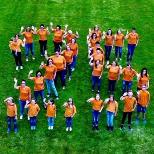 Gruppenfoto vom Basar-Team auf Rasen, aufgestellt in Form einer 25